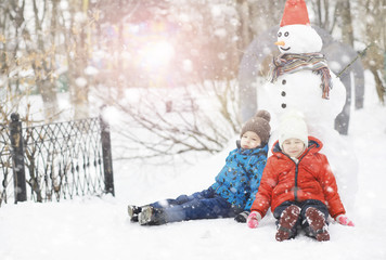 Children in the park in winter. Kids play with snow on the playground. They sculpt snowmen and slide down the hills.