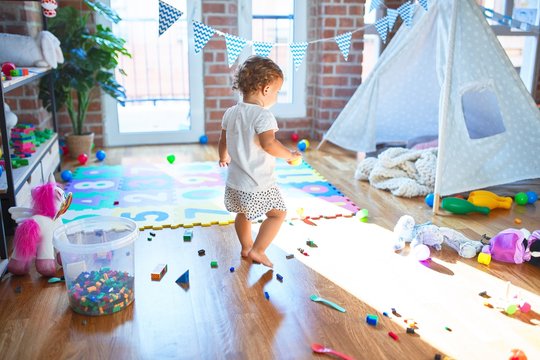 Adorable toddler playing around lots of toys at kindergarten