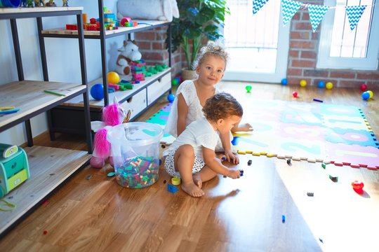 Beautiful toddlers playing around lots of toys at kindergarten
