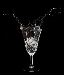 Glass cup with water splashes and ice cubes in the dark room