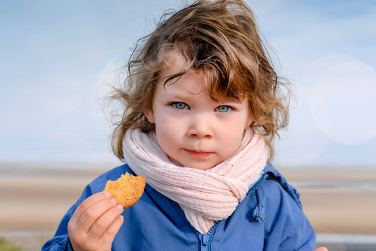 cute little girl eating a cookie outside