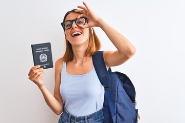 Beautiful redhead student woman wearing backpack and holding passport of italy with happy face smiling doing ok sign with hand on eye looking through fingers