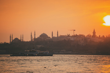 Istanbul Bosporus and city ferries with the silhouette of Hagia Sophia during sunset golden hour