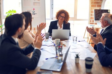 Group of business workers smiling happy and confident in a meeting. Working together looking at presentation using board and laptop applauding at the office.