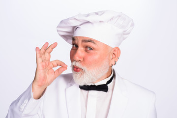 Old chef showing ok sign. Professional chef man in restaurant showing sign delicious. Male chef gesturing okay. Chef in cook uniform with perfect sign. Cook or baker gesturing. Taste.