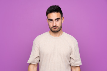 Fototapeta premium Young handsome man over isolated purple background with sad and depressed expression