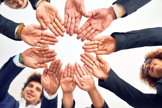 Group of business workers smiling happy and confident. Standing on a circle with smile on face doing symbol with hands together at the office.