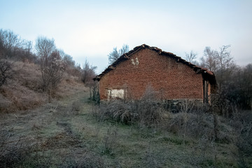 Obraz premium A series of misty landscapes in winter. Old barn near a road in a mountain village Smolichano in the Osogovo Balkan. Bulgaria.