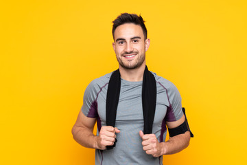Sport man over isolated yellow wall with sport towel - obrazy, fototapety, plakaty