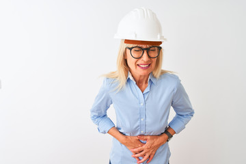 Middle age architect woman wearing glasses and helmet over isolated white background with hand on stomach because indigestion, painful illness feeling unwell. Ache concept.