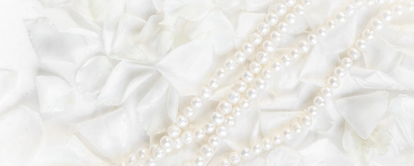 Pearl necklace on a background of white rose petals. Ideal for greeting cards for wedding, birthday, Valentine's Day, Mother's Day