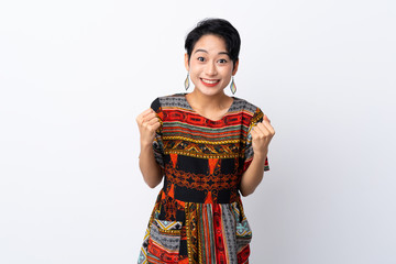 Young Asian girl with a colorful dress over isolated white background celebrating a victory in winner position