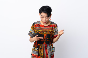 Young Asian girl with a colorful dress over isolated white background surprised and sending a message