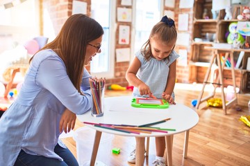 Caucasian girl kid playing and learning at playschool with female teacher. Mother and daughter at...
