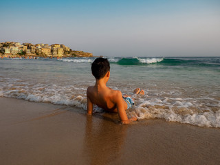 Closeup of an Asian boy relaxing on his back at the beach in the afternoon sunset.