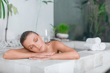 Young girl enjoys spa treatments in the bathroom with flowers.