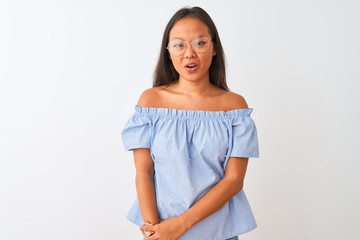 Young chinese woman wearing blue t-shirt and glasses over isolated white background afraid and shocked with surprise expression, fear and excited face.