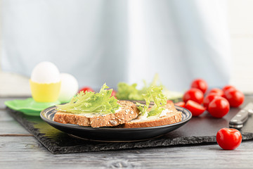 Sandwiches with soft cheese, lettuce and tomatoes on grain bread.