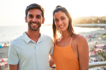 Fototapeta na wymiar Young beautiful couple on vacation smiling happy and confident. Standing with smile on face hugging at the beach