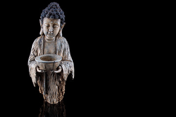 Freigestellte Buddha-Figur aus Holz mit einer Schale auf schwarzem Hintergrund und Platz für Text