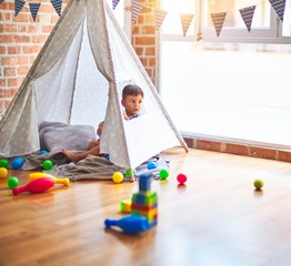 Beautiful toddler boy sitting on the floor playing inside  tipi at kindergarten © Krakenimages.com