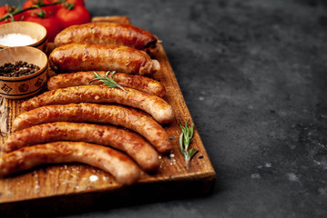 Various grilled sausages with spices on a stone table with copy space for your text.