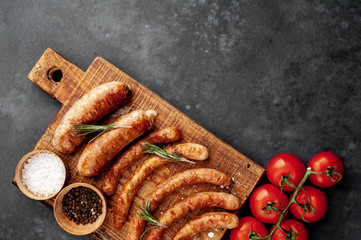 Various grilled sausages with spices on a stone table with copy space for your text.