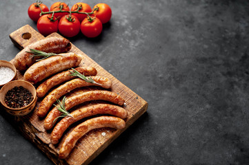 Various grilled sausages with spices on a stone table with copy space for your text.