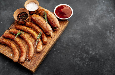 Various grilled sausages with spices on a stone table with copy space for your text.