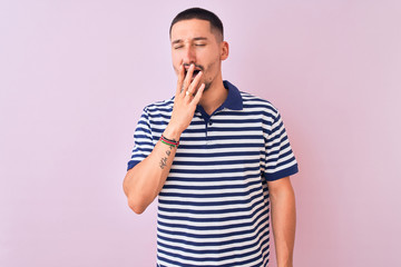 Young handsome man wearing nautical striped t-shirt over pink isolated background bored yawning tired covering mouth with hand. Restless and sleepiness.