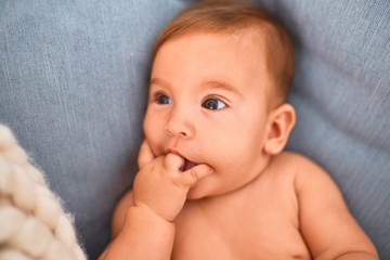 Adorable baby lying down over blanket on the sofa at home. Newborn relaxing and resting comfortable