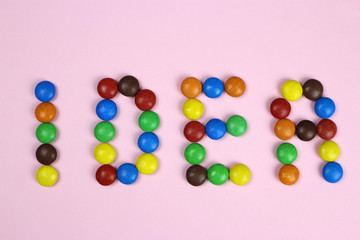 Word Idea of colored candies on a pink background