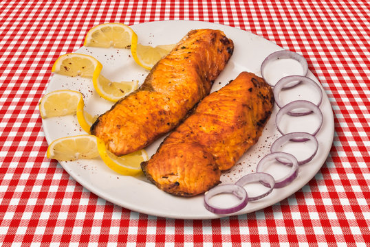Grilled fish fillet decorated with slised lemon and onion