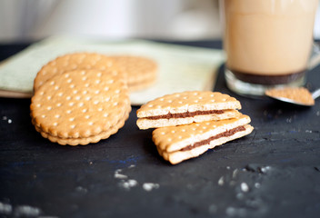 Cup of Coffee with a Cookies and brown shugar. Symbolic image. Coffee background. Sweet dessert. Wooden background. Close up. Freshly brewed cup of cafe latte coffee served with chocolate cookies