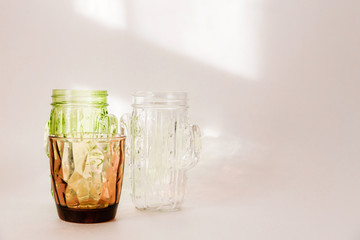 3 glasses - white, brown and green stand on a white background. Sunlight through glass  make a beautiful shade on white background by refraction of light.