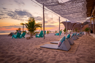 Beach club with chairs and umbrellas on beach during sunset © Michiel