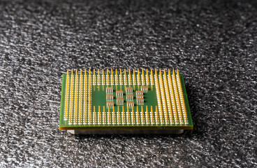 old computer processor with gold-plated legs, microcircuits on it, on a black soft substrate