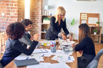 Group of business workers smiling happy and confident. Working together with smile on face. Middle age beautiful woman standing explaining documents at the office