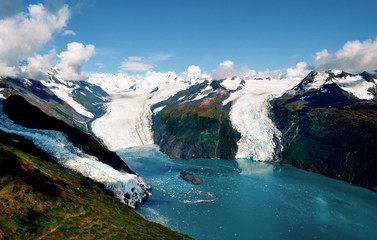 Aerial shot of three majestic glaciers calving into the beautiful azure blue waters of Prince William Sound, Kenai Peninsula. Icebergs float in the water below - Alaska - obrazy, fototapety, plakaty