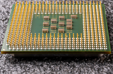 old computer processor with gold-plated legs, microcircuits on it, on a black soft substrate...