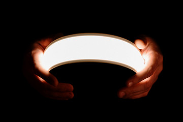 Flexible lighting oled panels in male hands on a black background