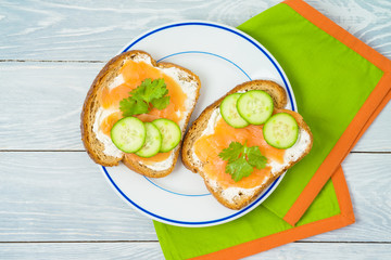 Food and healthy eating concept. Smoked salmon sandwich with cream cheese on wooden table.