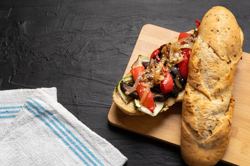 Vegan sub sandwich with grilled vegetables on dark background