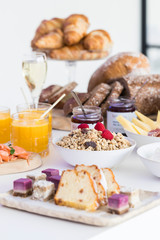 Luxurious gourmet breakfast table, presented with granola, champagne, croissants, juice, cake, bread and more