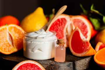 Concept of natural fruity organic ingredients in cosmetology. Extract of grapefruit for moisturizing, delicate skin nutrition, pore narrowing and anti-cellulite effect. Wooden background, copy space
