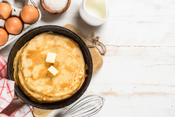 Crepes or thin pancakes in the frying pan with ingredients for cooking.