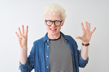 Young albino blond man wearing denim shirt and glasses over isolated white background showing and pointing up with fingers number nine while smiling confident and happy.