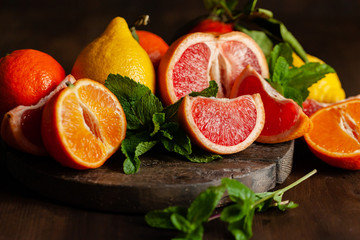 Slices of ripe fresh organic citrus fruits: grapefruit, orange, lemon on wooden board. Natural source of vitamins, low calories tasty dessert. Dark background, close up, front view