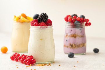 3 homemade yoghurts /plant based fruit desserts on bright stone surface