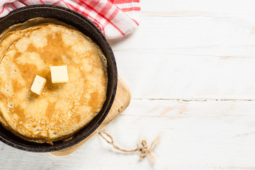 Crepes in the frying pan on white table.